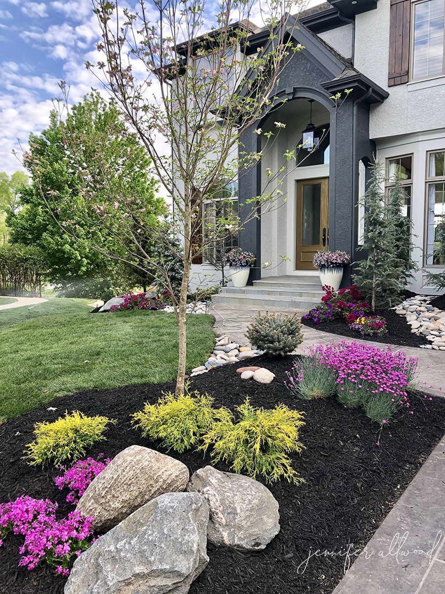 dark mulch with green and pink plants and big rocks