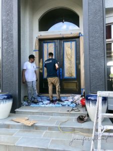 two contractors helping spray the front door gold
