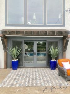 arbor above pool door with agave plants in blue planters